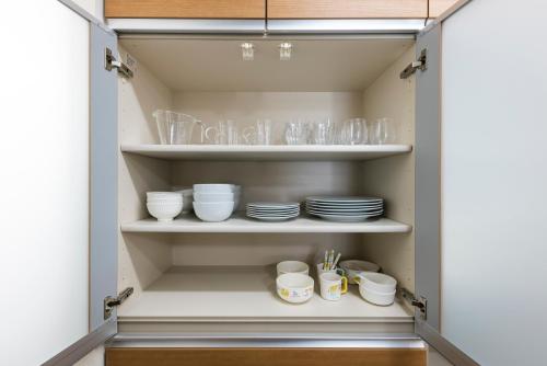 a cupboard with plates and glasses in it at Mukae House in Kumamoto