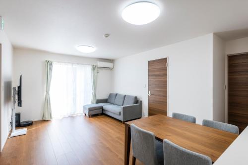 a living room with a table and a couch at Mukae House in Kumamoto