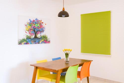 comedor con mesa de madera y sillas coloridas en Hospedaje Aldana Apartamento AURA Centro Histórico, en Tuxpan de Rodríguez Cano