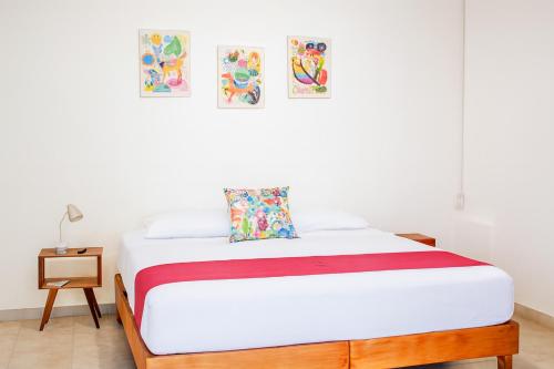 Un dormitorio con una cama con sábanas blancas y cuadros en la pared. en Hospedaje Aldana Apartamento AURA Centro Histórico, en Tuxpan de Rodríguez Cano