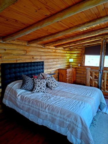 una camera con un letto in una baita di tronchi di La Autóctona a Villa Yacanto