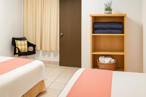 a hotel room with two beds and a chair at Hospedaje Aldana - Apartamento AMAL zona centro in Tuxpan de Rodríguez Cano