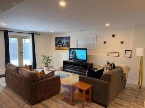 a living room with two couches and a flat screen tv at Cozy Home Away from Home in Kingston