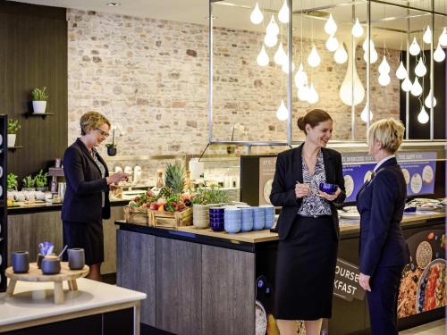 Dos mujeres de pie frente a un mostrador en una cocina. en Novotel Frankfurt City, en Frankfurt