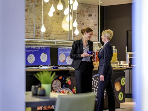 dos mujeres de pie en una cocina hablando en Novotel Frankfurt City, en Frankfurt
