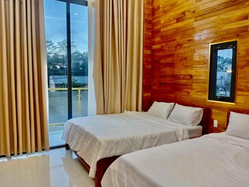 zwei Betten in einem Hotelzimmer mit Fenster in der Unterkunft Homestay Hera Mang Den in Kon Plong