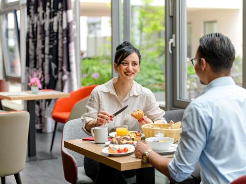 Um homem e uma mulher sentados à mesa a comer. em Mercure Hotel Stuttgart Airport Messe em Estugarda