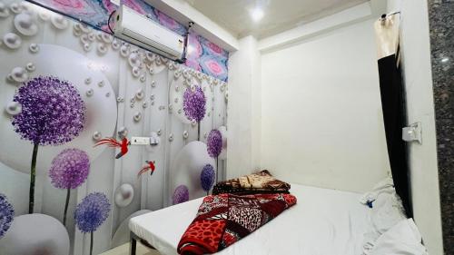 a small bedroom with purple flowers on the wall at Hardik Guest House & General Store in Rīngas