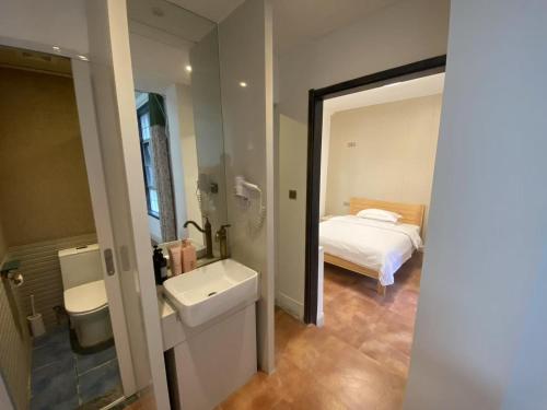 een badkamer met een wastafel, een bed en een spiegel bij Half-City Homestay in Xi'an