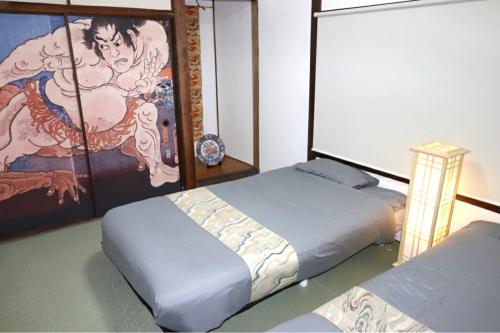 a bedroom with two beds and a painting on the wall at インジホテル下関 in Shimonoseki