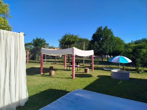 a tent and an umbrella in a park at Aires Verdes in General Pico