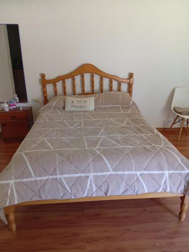 a bed with a wooden frame with a gray comforter at Aires Verdes in General Pico