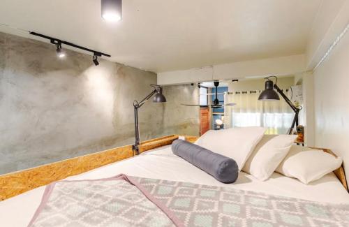 a bedroom with a large white bed with two lights at Bang Chak Studio in Bangkok