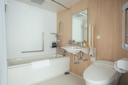 a bathroom with a sink and a tub and a toilet at Kuretake Inn Okayama in Okayama
