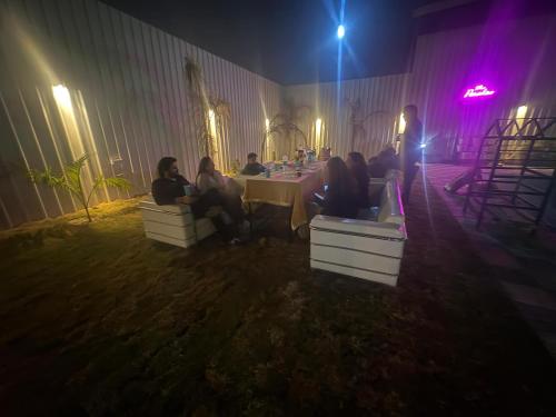 een groep mensen die 's nachts aan een tafel zitten bij The Paradise farm stay in Ghaziabad