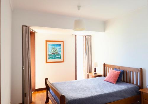 a bedroom with a bed with a blue blanket and a window at Barramares Pool & Beach in Ovar