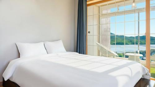 Un dormitorio con una cama blanca grande y una ventana en Yeongheungdo noeul&bada pension, en Incheon