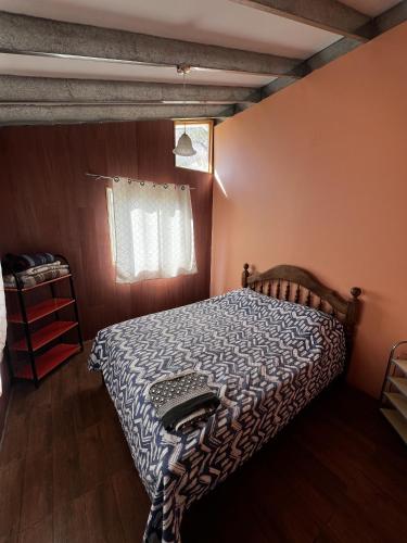 a bedroom with a bed with a comforter and a window at Cabañas Pisco Elqui in Pisco Elqui