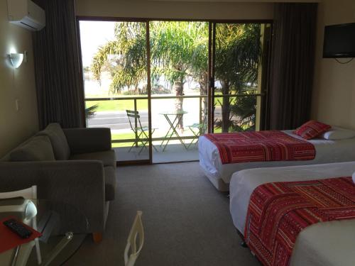 a hotel room with two beds and a balcony at Abel Tasman Waterfront Motel in Lakes Entrance