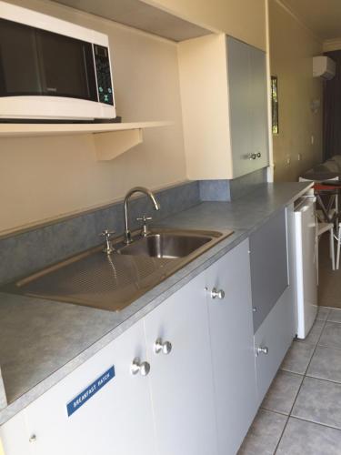 a kitchen with a sink and a microwave at Abel Tasman Waterfront Motel in Lakes Entrance