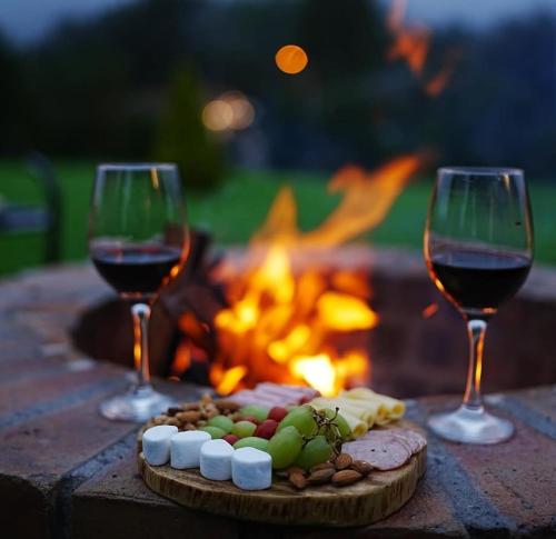 Twee glazen wijn en een bord eten naast een vuurkorf. bij Glamping Al Pie del Cerro in San Fernando