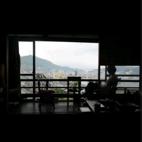 a person sitting on a bench looking out of a window at O19 Tea Celemony Villa in Onomichi