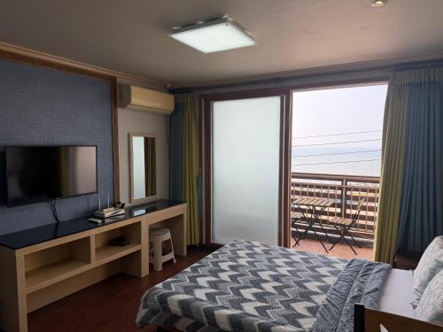 a hotel room with a bed and a television and a balcony at Yangji Resortel in Hwaseong