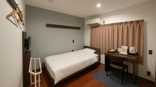 um pequeno quarto com uma cama e uma secretária com uma secretária. em Kawabata Ryokan Takehara by Tabist em Takekara