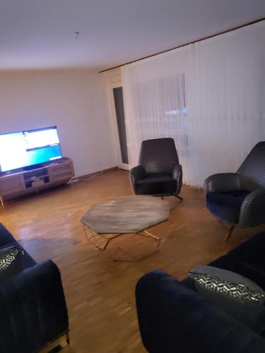 ein Wohnzimmer mit zwei Stühlen und einem Flachbildfernseher in der Unterkunft Le relais du Marronnier in Grandsivaz