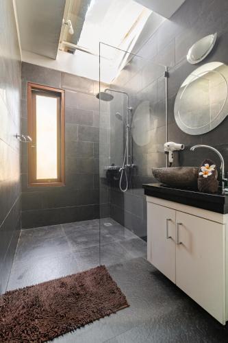 a bathroom with a shower with a sink and a mirror at Singaraja Sea View Villa in Singaraja