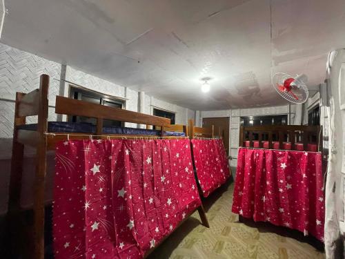 a row of beds in a room with red sheets at Hondelz Budget Homestay in Busuanga
