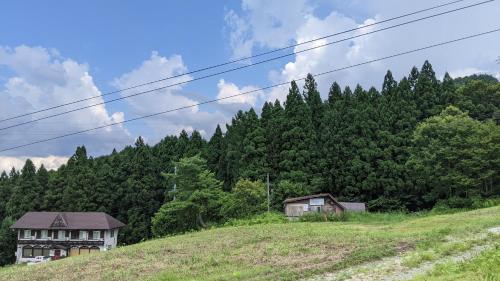 two houses on a hill with trees in the background at Red Gate Lodge in Kijimadaira