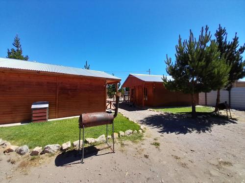 a rusty object in a yard next to a building at Cabañas San Benito in Los Antiguos
