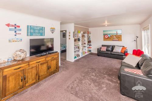 Una sala de estar con un sofá y un televisor de pantalla plana. en Sandy Escape, en Sandy Point