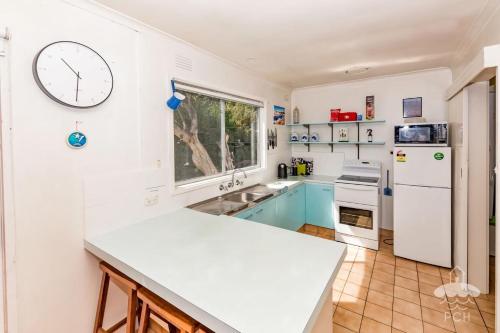 una cocina con electrodomésticos blancos y un reloj grande en la pared en Sandy Escape, en Sandy Point