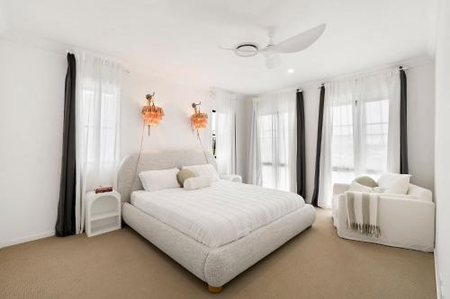 a white bedroom with a large white bed and windows at Holiday Haven on Spoonbill Pet Friendly with Pool in Kingscliff
