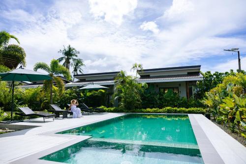 Una novia parada frente a una casa con piscina. en Bellamar Villas, en El Nido