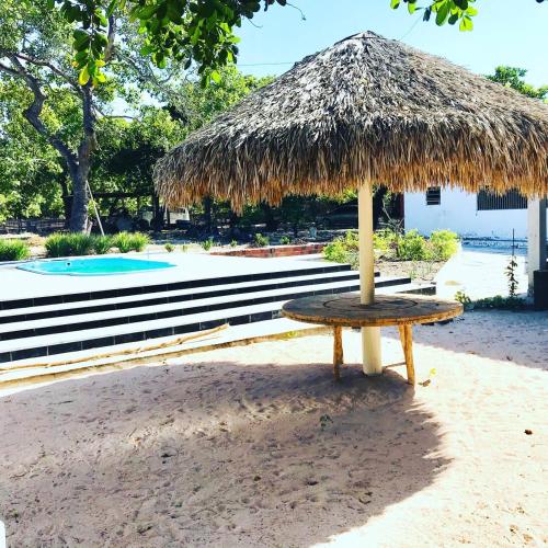 einen Tisch mit einem Strohschirm am Strand in der Unterkunft Pousada o Rancho in Jijoca de Jericoacoara