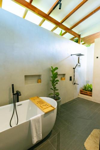 a bathroom with a bath tub and a plant at Bellamar Villas in El Nido
