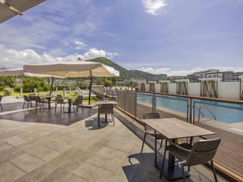Un patio con mesas y sillas y una piscina. en Novotel Salerno Est Arechi, en Salerno
