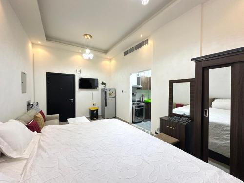 a bedroom with a large white bed and a television at Entire Studio Apartment Beside Oasis towers in Ajman 