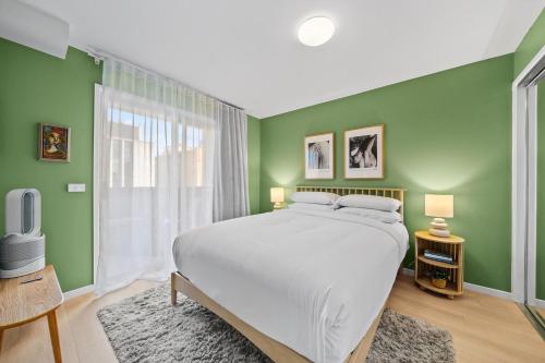 a bedroom with a large bed and green walls at Stylish 1-Bed Unit with Secure Parking in Braddon