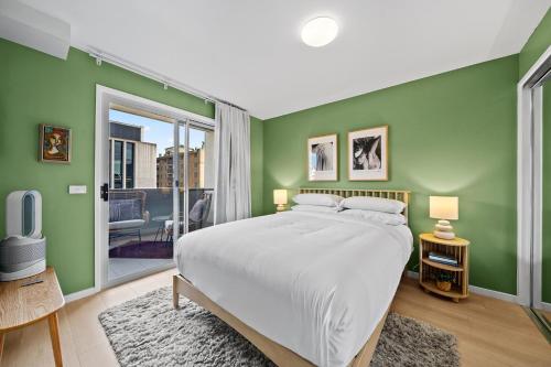 a bedroom with a large bed and green walls at Stylish 1-Bed Unit with Secure Parking in Braddon