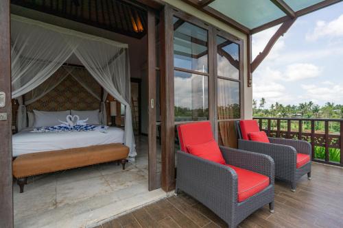 a bedroom with a bed and two chairs on a deck at Uma Stana Villa in Ubud