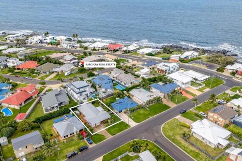 an aerial view of a residential neighbourhood next to the ocean at 12 Wilfred Street in Bargara