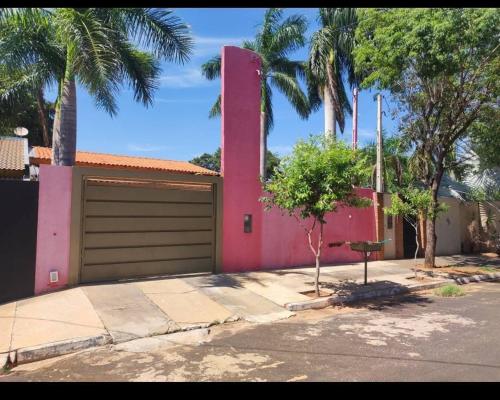 una casa rosa con garage e palme di Rancho Aconchego para seu lazer a Panorama