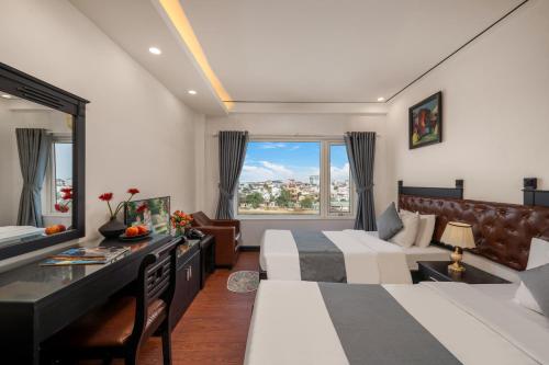 a hotel room with two beds and a desk at Vina Spa Hotel in Hue