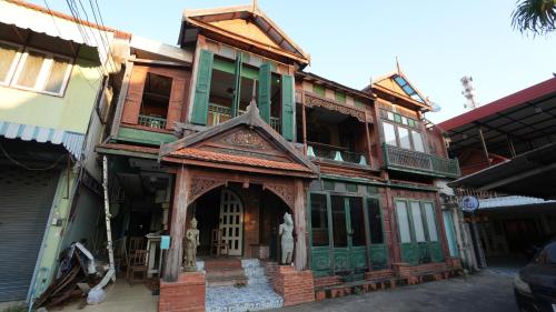 an old house with a building with green windows at The Florist Ayutthaya in Phra Nakhon Si Ayutthaya