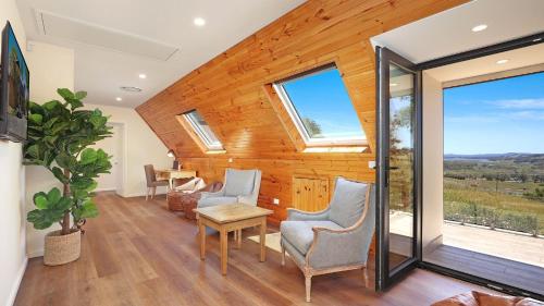 ein Wohnzimmer mit Stühlen, einem Tisch und Fenstern in der Unterkunft Goolara in Burrawang