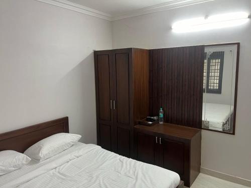 une chambre avec un lit, une commode et un miroir dans l'établissement Raj Nivas, à Mayiladuthurai